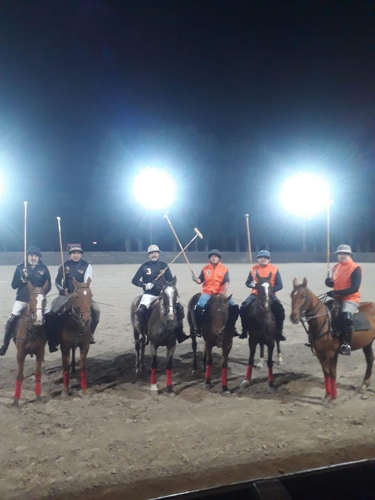 polo players posing in illuminated arena polo field